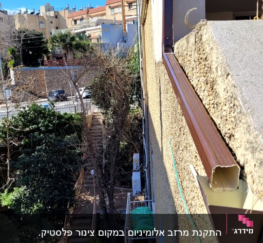 מרזב חום מחובר לגג עם רעפים חומים